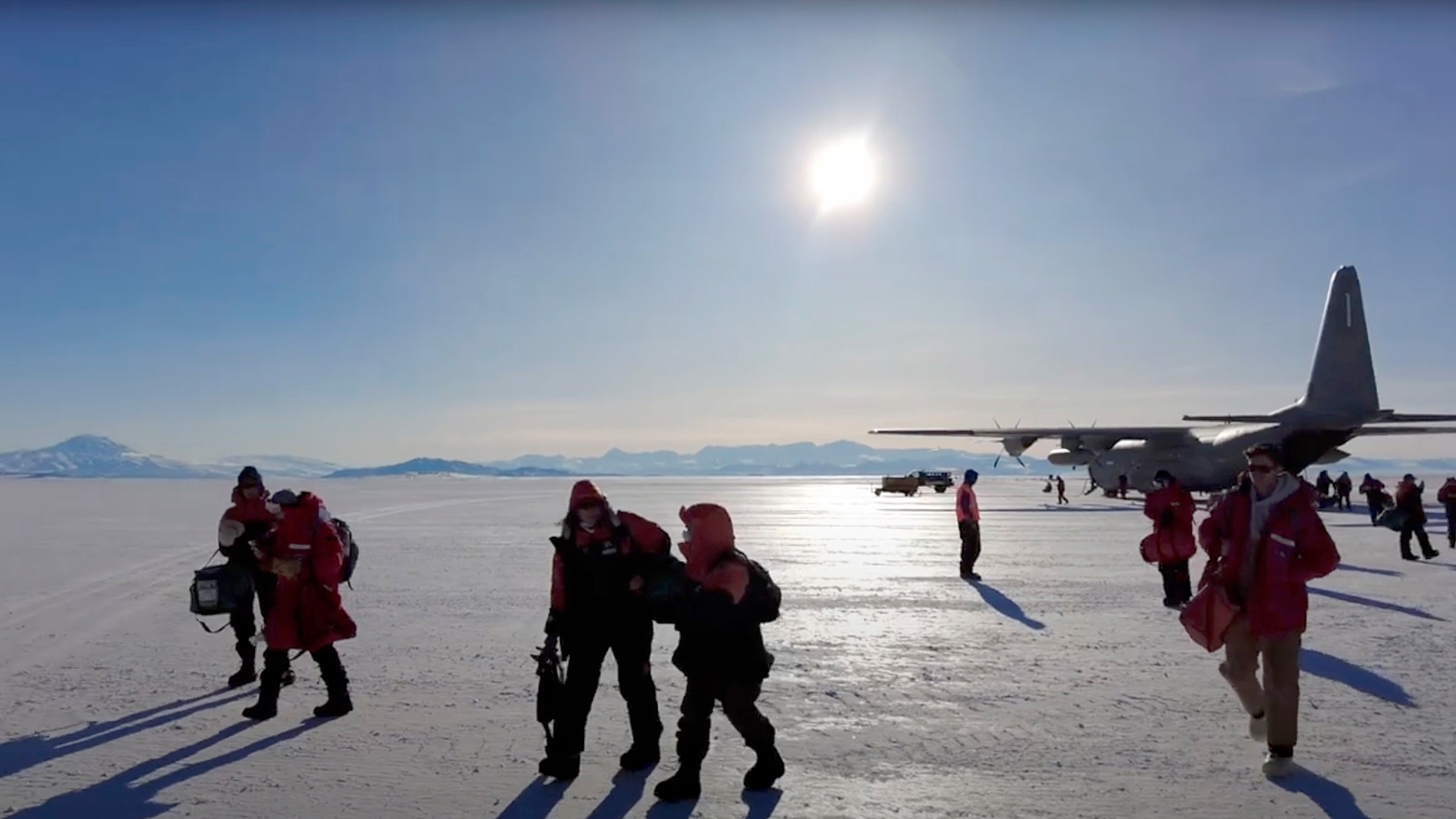 A group of people walking from an airplane in Antarctica.